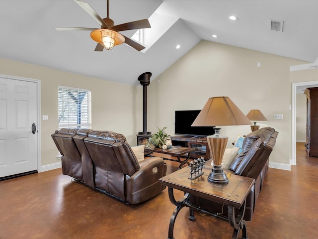 living area featuring concrete flooring, a wood stove, ceiling fan, and baseboards