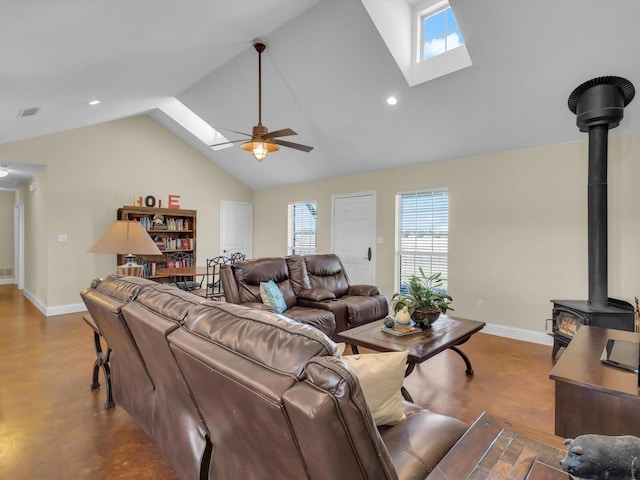 living area with ceiling fan, a skylight, a wood stove, and baseboards