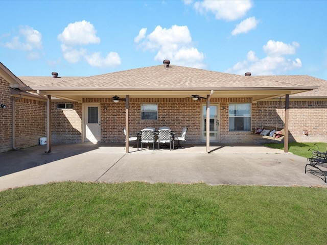 back of house with brick siding, a patio, a shingled roof, a lawn, and ceiling fan