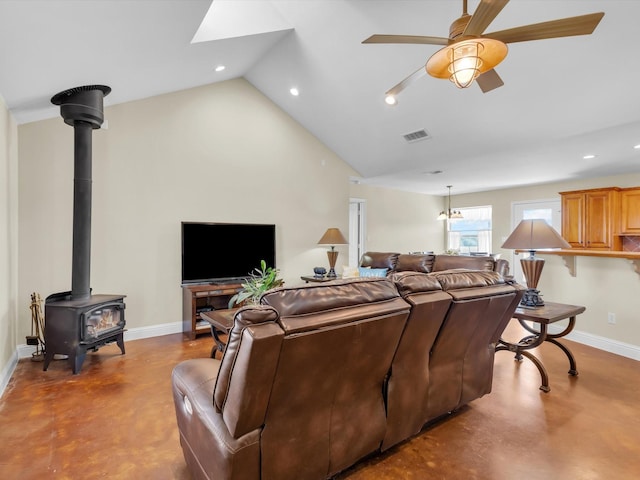 living room with baseboards, visible vents, a wood stove, vaulted ceiling, and concrete floors