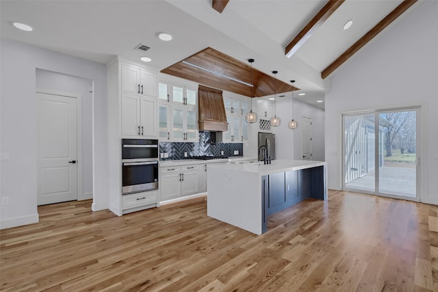 kitchen featuring visible vents, appliances with stainless steel finishes, custom exhaust hood, light countertops, and white cabinetry