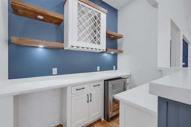 kitchen featuring wine cooler, light wood finished floors, open shelves, light countertops, and white cabinetry