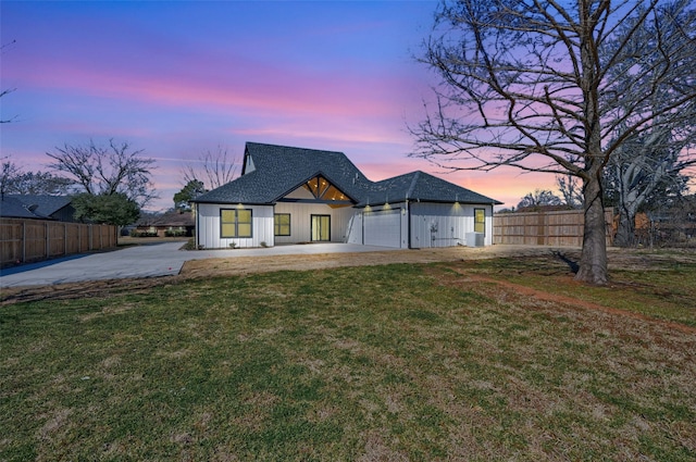 back of house with a shingled roof, fence, and a lawn