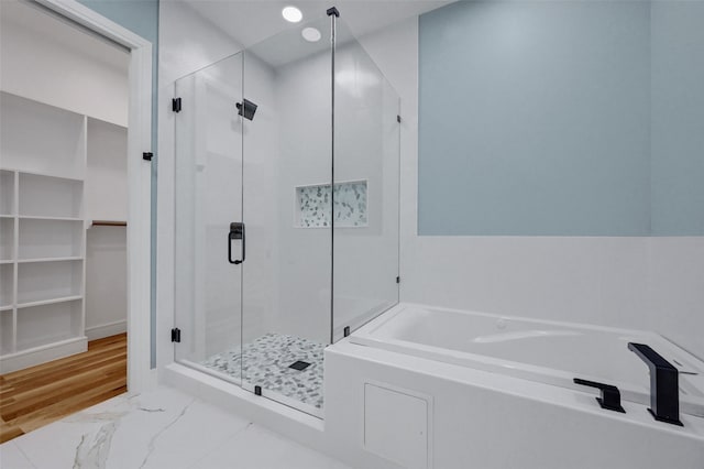 bathroom with marble finish floor, a shower stall, a walk in closet, and a bath