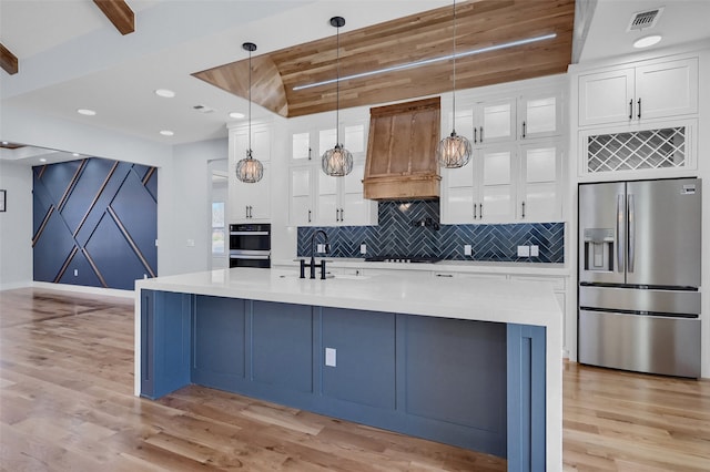 kitchen with light wood finished floors, tasteful backsplash, visible vents, stainless steel appliances, and a sink