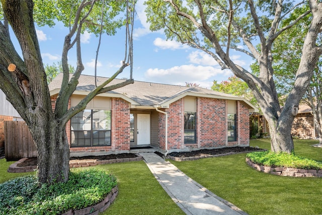 view of front facade featuring a front yard, brick siding, fence, and roof with shingles