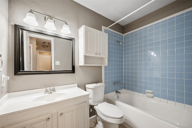 bathroom featuring toilet, a textured wall, shower / tub combination, and vanity