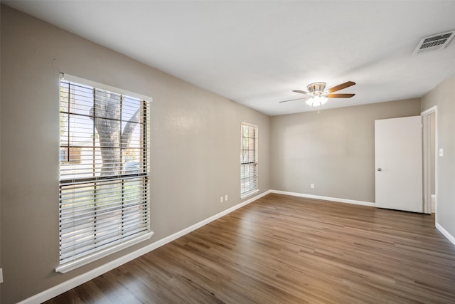 unfurnished room featuring ceiling fan, wood finished floors, visible vents, and baseboards