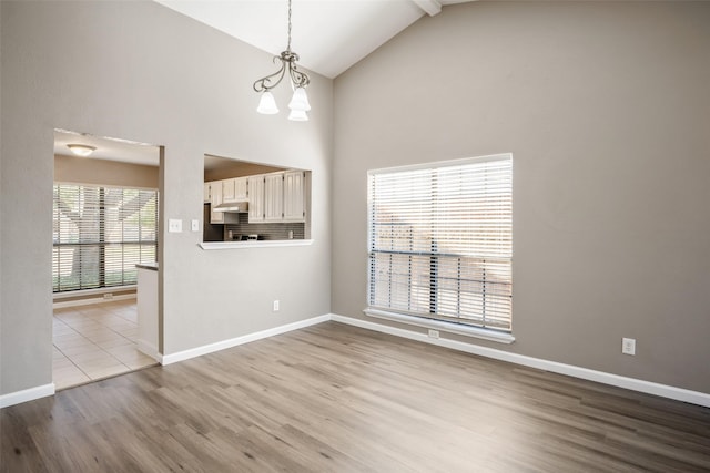 interior space with a chandelier, high vaulted ceiling, baseboards, and wood finished floors