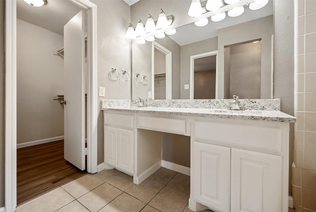 full bathroom with a sink, double vanity, tile patterned flooring, and a walk in closet