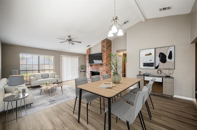 dining room with a brick fireplace, wood finished floors, and visible vents