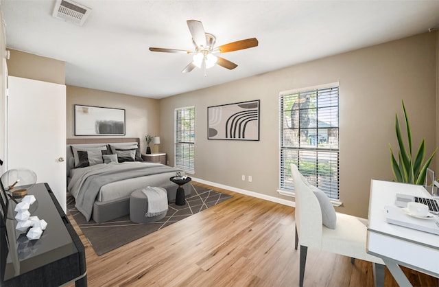 bedroom with baseboards, visible vents, multiple windows, and wood finished floors