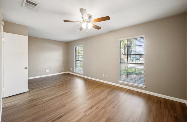 spare room with visible vents, ceiling fan, baseboards, and wood finished floors