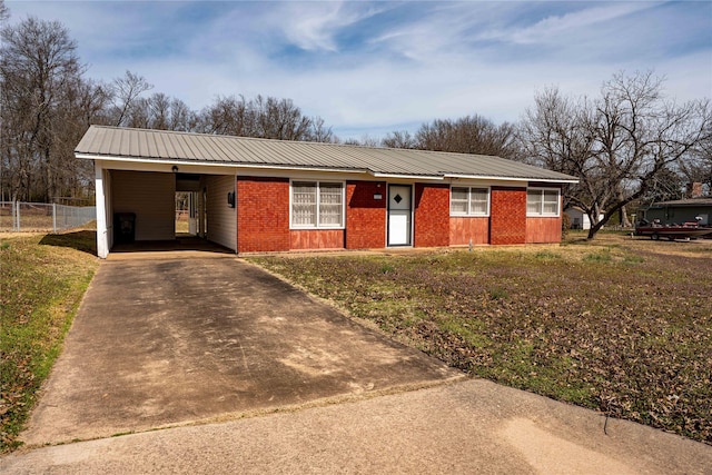 ranch-style house featuring concrete driveway, an attached carport, metal roof, fence, and brick siding