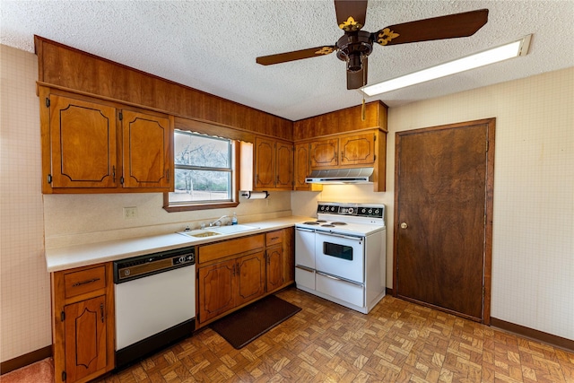 kitchen with a textured ceiling, under cabinet range hood, white appliances, a sink, and light countertops