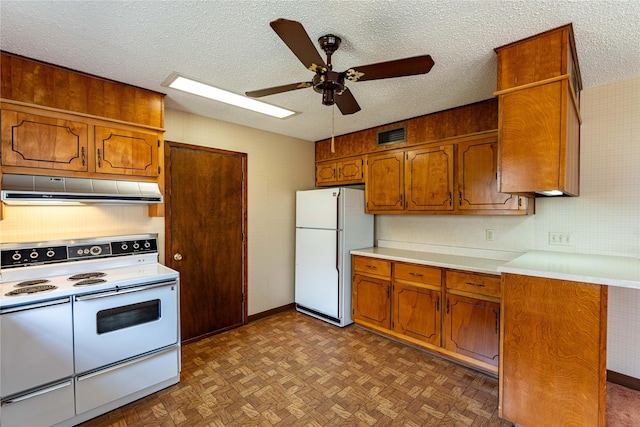 kitchen with a textured ceiling, under cabinet range hood, white appliances, light countertops, and brown cabinetry