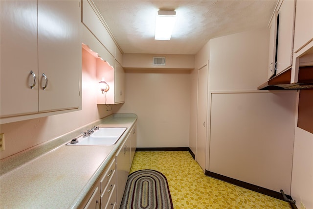 kitchen featuring visible vents, white cabinets, light countertops, light floors, and a sink