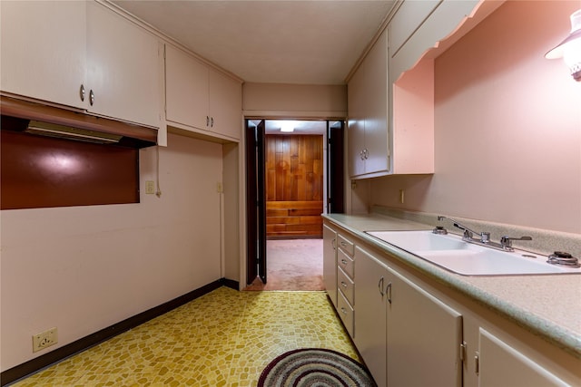 kitchen with light countertops, a sink, and baseboards