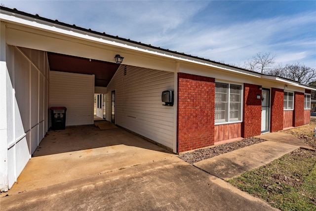 exterior space featuring a carport, brick siding, and concrete driveway