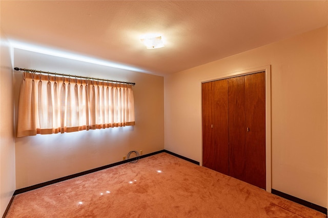 unfurnished bedroom with carpet floors, baseboards, and a closet