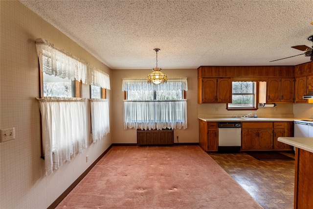 kitchen featuring light countertops, brown cabinets, dishwasher, and a textured ceiling