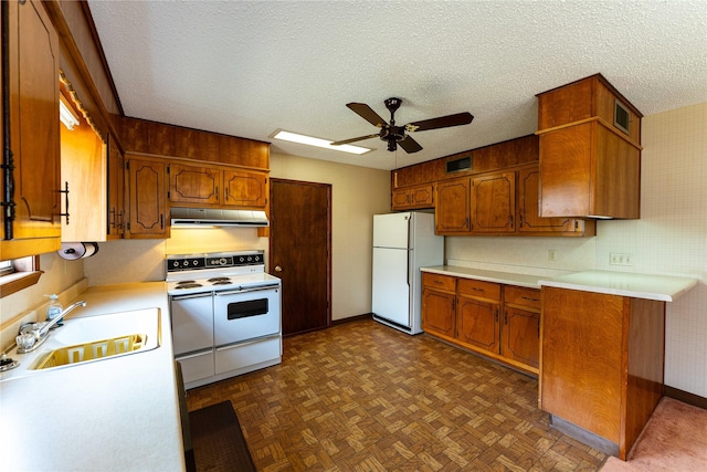 kitchen with a textured ceiling, under cabinet range hood, white appliances, a sink, and brown cabinetry