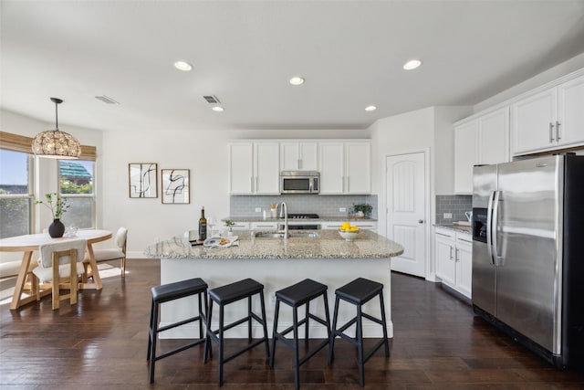 kitchen featuring stainless steel appliances, visible vents, a sink, and dark wood-style floors