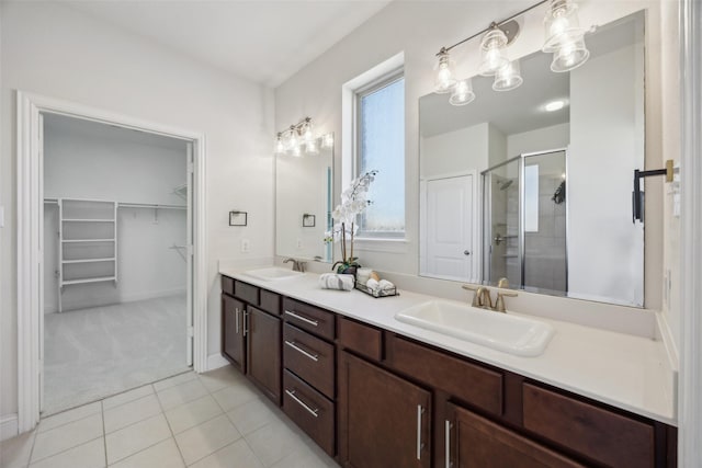 bathroom with double vanity, a stall shower, tile patterned flooring, and a sink