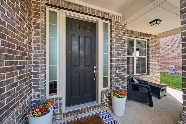 entrance to property featuring covered porch and brick siding