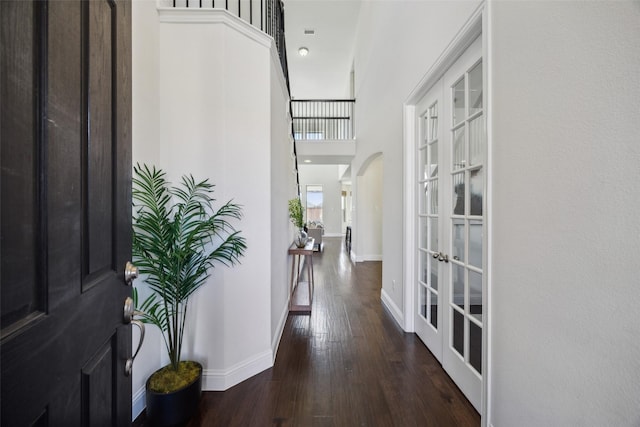 foyer entrance with arched walkways, wood-type flooring, french doors, and baseboards