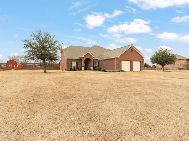 view of front of house featuring an attached garage, brick siding, fence, a front lawn, and a chimney