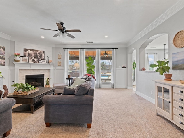 carpeted living area with crown molding, a brick fireplace, and plenty of natural light