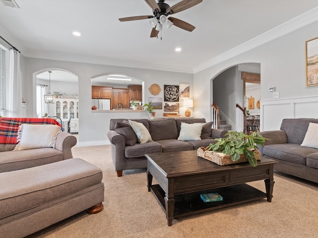 living room featuring stairway, arched walkways, ornamental molding, and light colored carpet