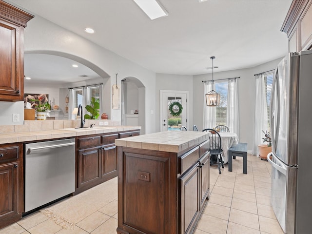 kitchen featuring appliances with stainless steel finishes, a sink, dark brown cabinets, and light tile patterned floors