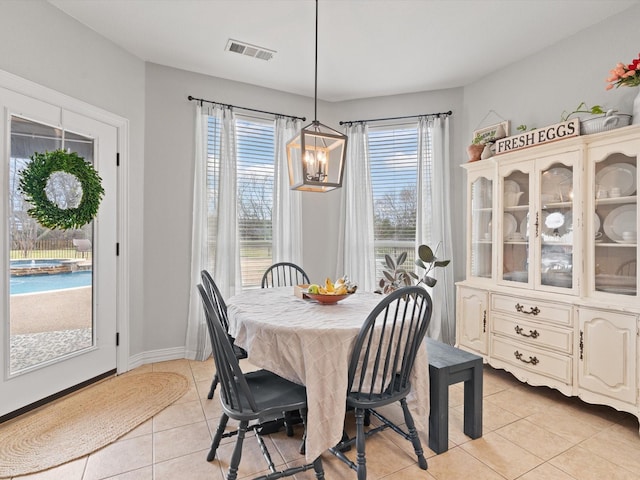 dining room featuring a chandelier, light tile patterned flooring, visible vents, and baseboards