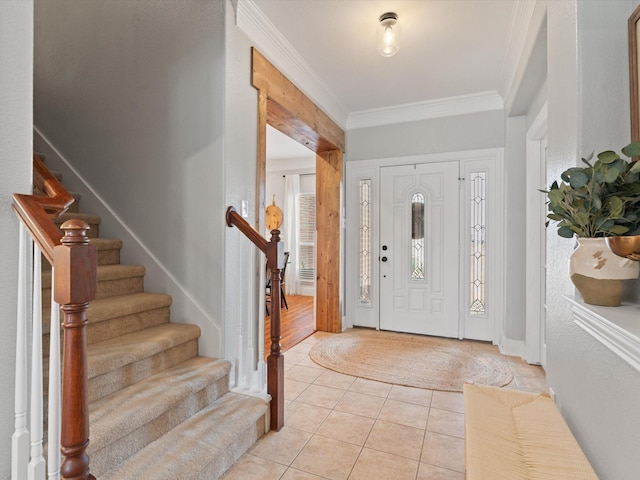 foyer entrance with light tile patterned floors, ornamental molding, and stairway