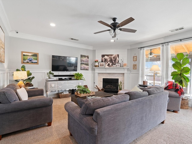 living area with wainscoting, ornamental molding, a brick fireplace, and visible vents