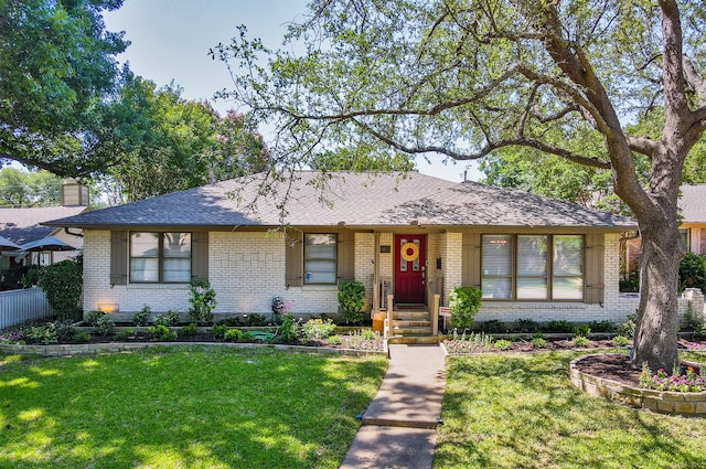 ranch-style home featuring a front lawn, roof with shingles, and brick siding