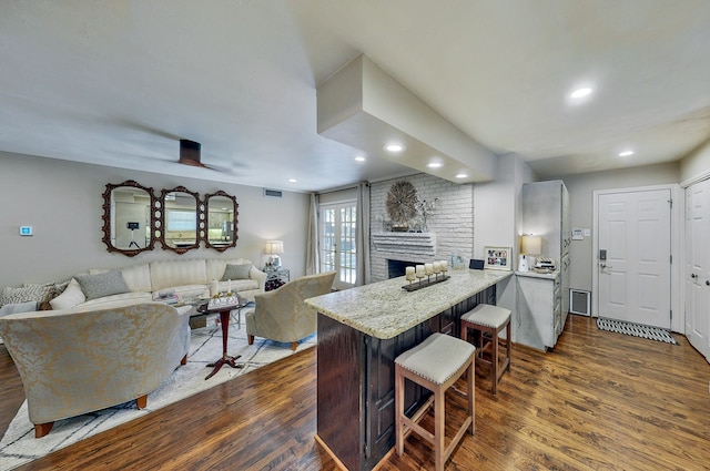 kitchen featuring visible vents, dark wood finished floors, a peninsula, and a kitchen bar