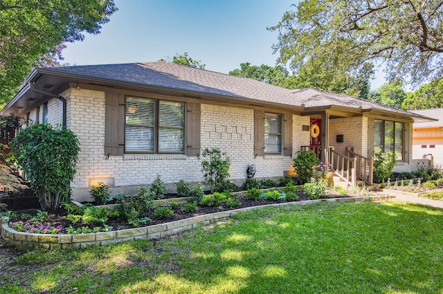 ranch-style house with a front yard, brick siding, and roof with shingles