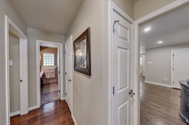 corridor with dark wood-style floors, baseboards, and recessed lighting