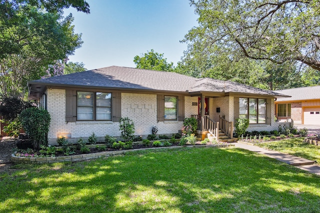 view of front of property featuring a shingled roof, brick siding, and a front lawn