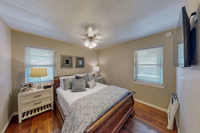 bedroom with ceiling fan, multiple windows, wood finished floors, and baseboards