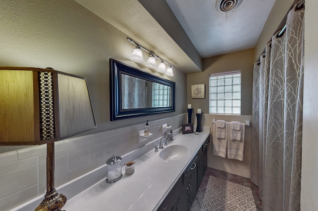 full bathroom with a textured ceiling, vanity, tile walls, wainscoting, and tile patterned floors