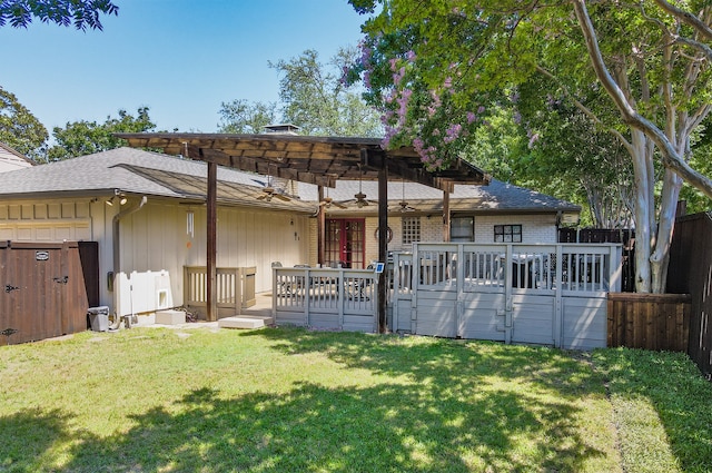 view of front of house with brick siding, a ceiling fan, a front yard, fence, and a deck