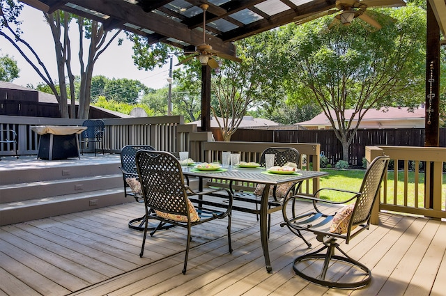 wooden terrace featuring a yard, outdoor dining area, ceiling fan, and fence