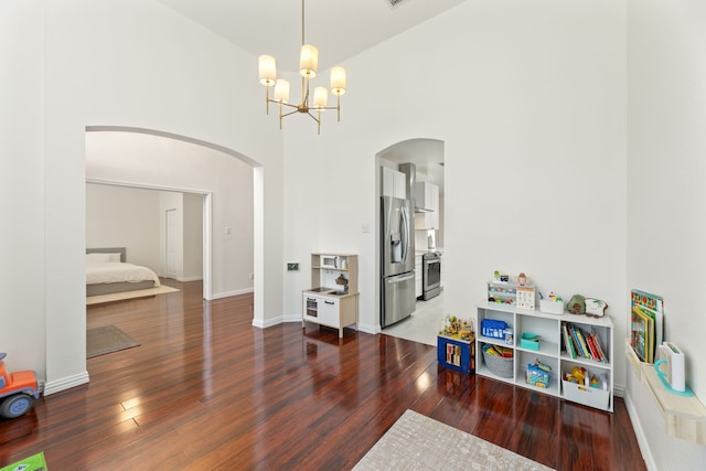 playroom featuring hardwood / wood-style flooring, baseboards, a high ceiling, and arched walkways