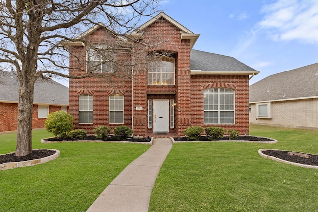 traditional-style house featuring a front yard, brick siding, and roof with shingles