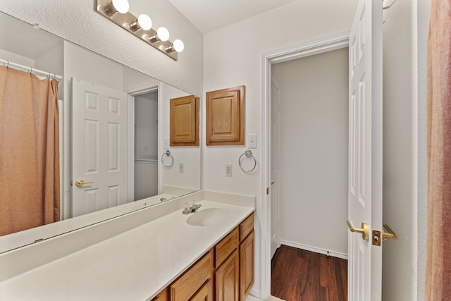 full bathroom with wood finished floors, vanity, and baseboards