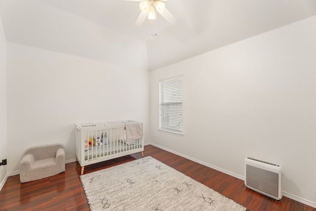 bedroom featuring lofted ceiling, ceiling fan, wood finished floors, baseboards, and a nursery area